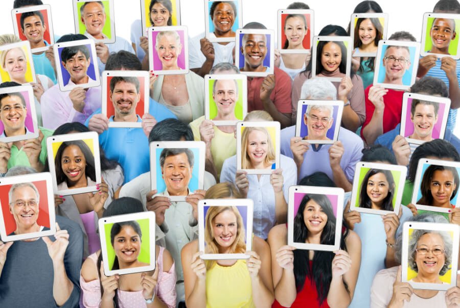 Demographic group of people of different age ranges holding up self-portraits on tablet computers