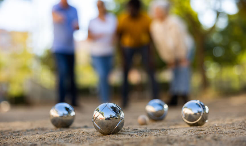 Members of a social club playing petanque outdoors.