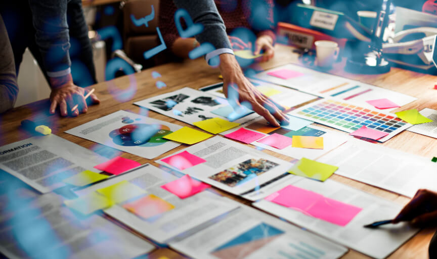 Participants engage in a workshop training session, with brainstorming materials laid out on a work surface.