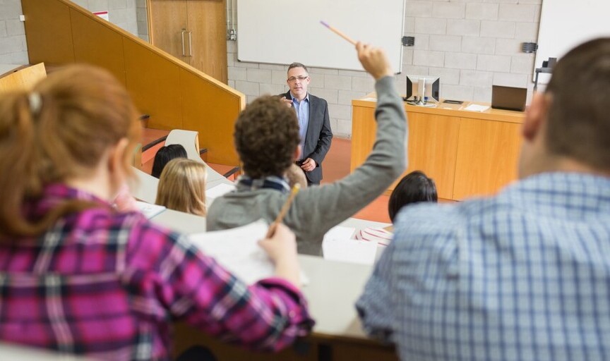 Students attend a seminar, sitting in a lecture theatre looking toward the tutor.