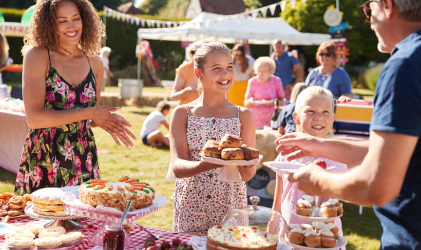 Volunteers serve at a cake stall at a busy charity fundraising fete.