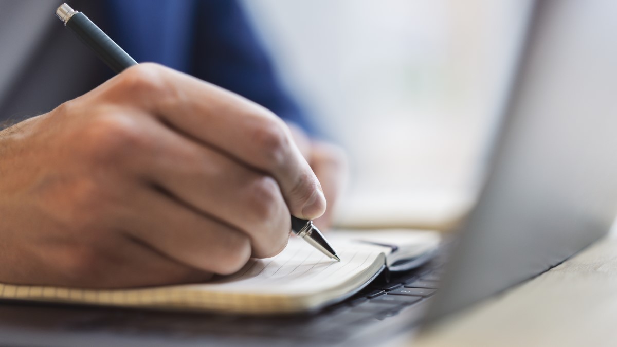 Man taking notes on how to improve his writing of survey titles